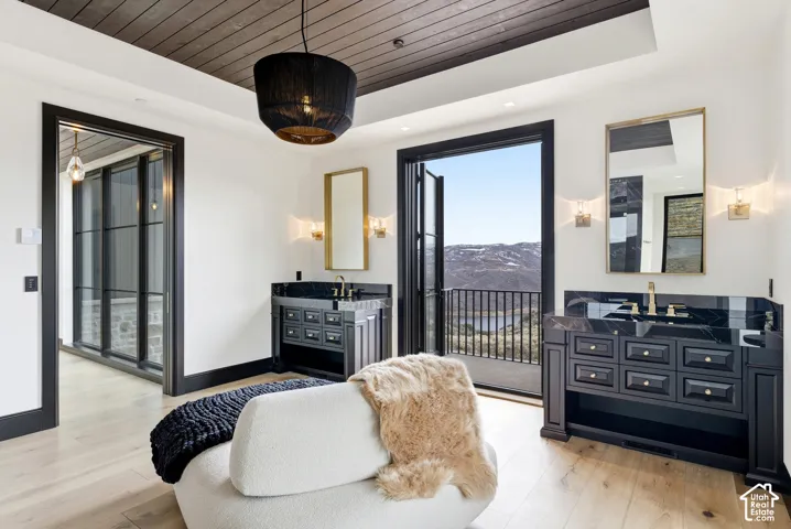 Wood-finish flooring, dark wood plank ceiling, and dual vanity areas with dark countertops and gold-toned fixtures