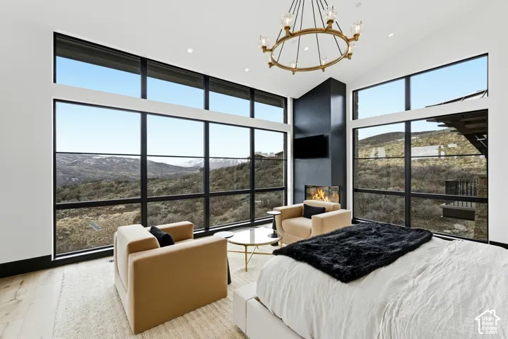 Expansive window walls with black frames, modern fireplace, integrated media niche, and a contemporary chandelier