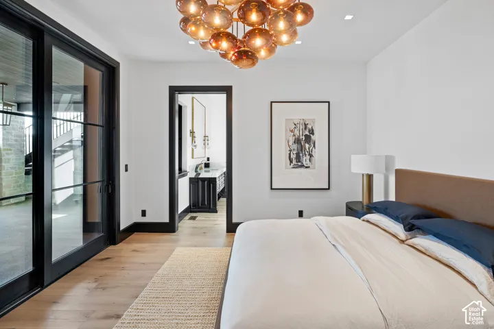 Hardwood flooring throughout, black-framed sliding glass doors, contemporary chandelier, recessed ceiling lighting, and black door trim