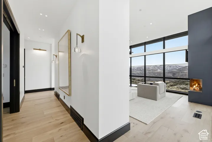 Light wood-finish flooring extending into a spacious living area with expansive floor-to-ceiling windows