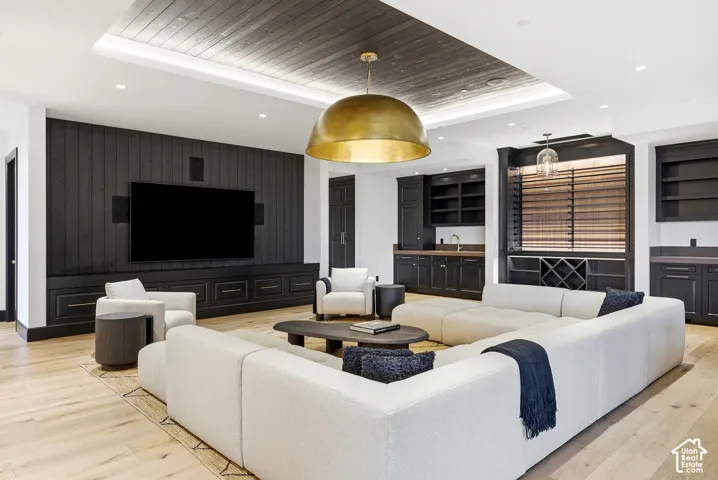 Wood-finish flooring, recessed lighting, and a dark wood-paneled accent wall with built-in cabinetry