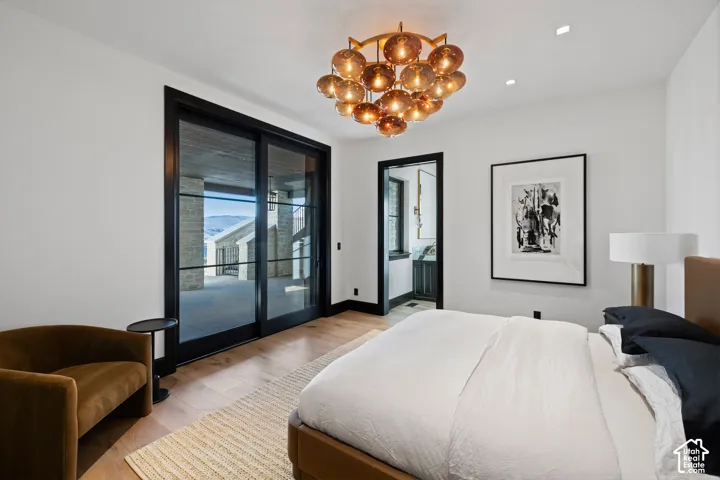 Wood-finish flooring with a large area rug, black-framed sliding glass doors, and a decorative chandelier
