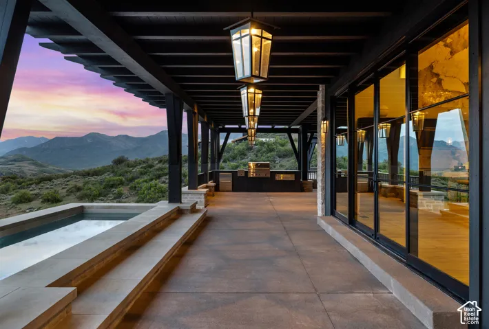 Expansive outdoor patio with a built-in spa, outdoor kitchen, and large sliding glass doors