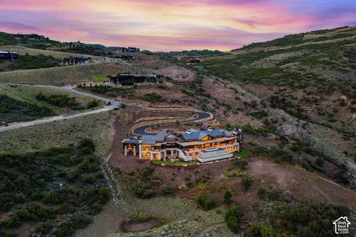 Sprawling hillside residence featuring extensive exterior lighting, multiple terraces, and a distinct roofline