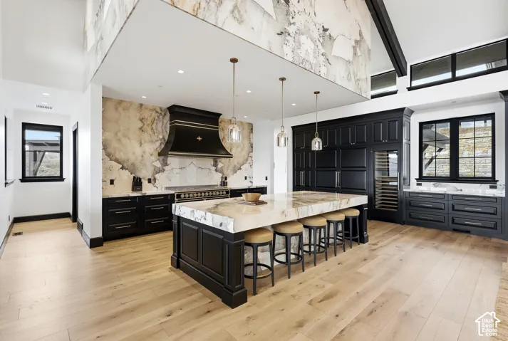 Hardwood flooring throughout, featuring a large kitchen island with seating, dark wood cabinetry, and a built-in wine refrigerator