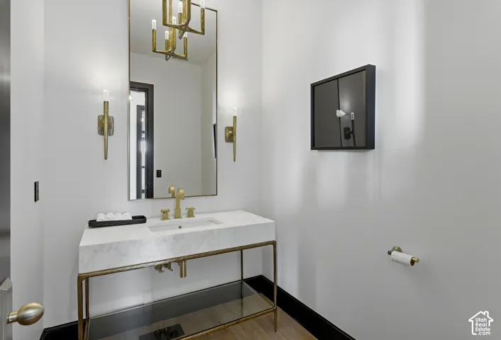 Recessed sink with a stone countertop, brass-finish faucet, and a large wall-mounted mirror