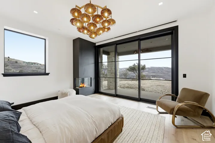 Contemporary built-in fireplace, large picture window with dark trim, expansive sliding glass doors, overhead decorative lighting fixture, and wood-finish flooring