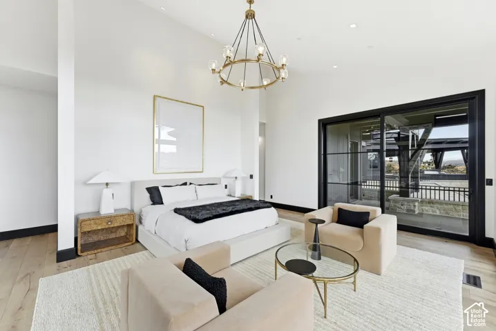 Vaulted ceilings, wood-finish flooring, a contemporary chandelier, recessed lighting, and a large black-framed sliding glass door