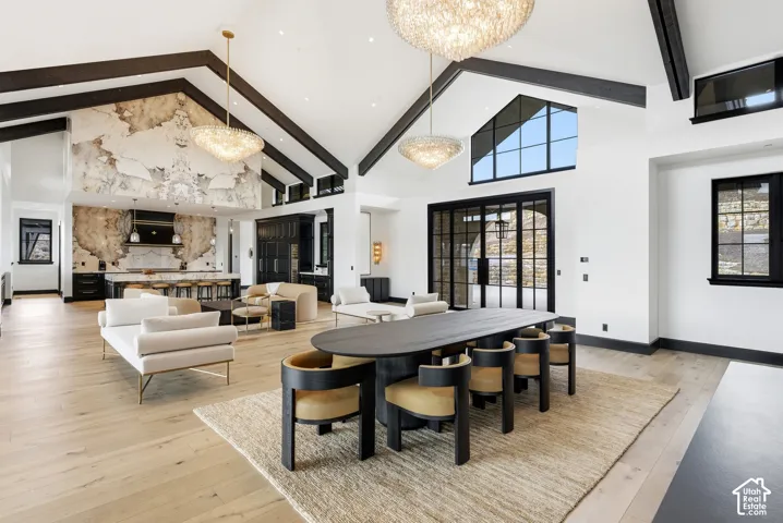 Vaulted ceilings with exposed dark wood beams, light wood-finish flooring, and a stone accent wall
