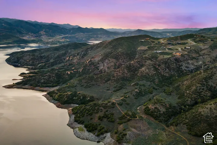 Expansive waterfront property featuring mountainous terrain, mature greenery, and a serene water body