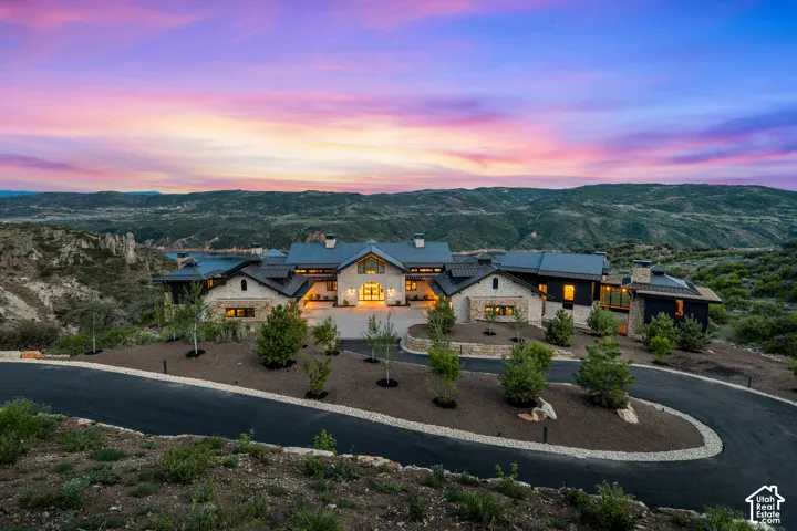 Expansive property featuring a stone and dark exterior, multi-gabled roofline, and a paved circular driveway
