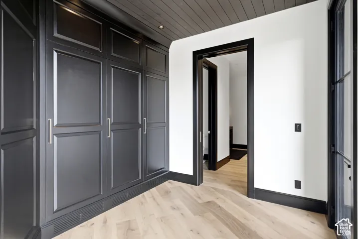 Custom built-in cabinetry with paneling, contrasting trim, wood-finish flooring, and a textured ceiling