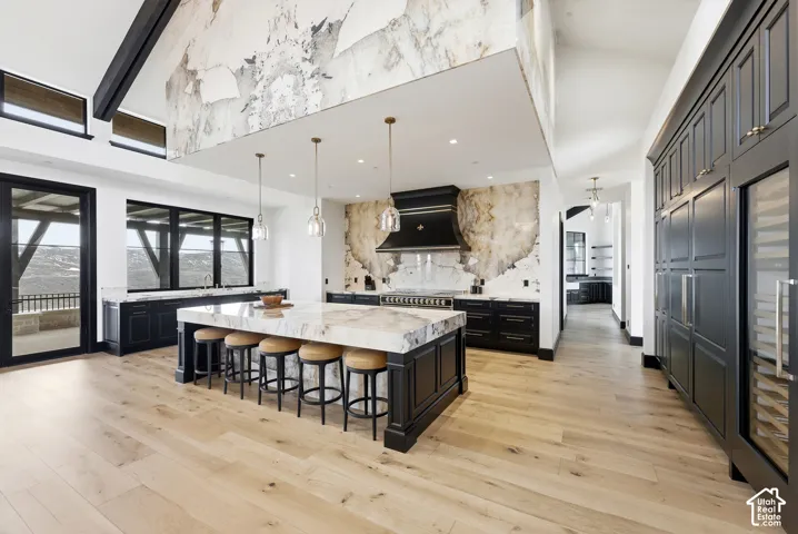 Spacious kitchen featuring an expansive central island with seating, integrated appliances, wood-finish flooring, and a large sliding glass door