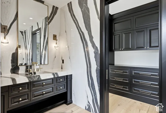 Spa-inspired primary bathroom featuring a double vanity with black cabinetry and brushed metal hardware, white quartz countertops, and vessel sinks