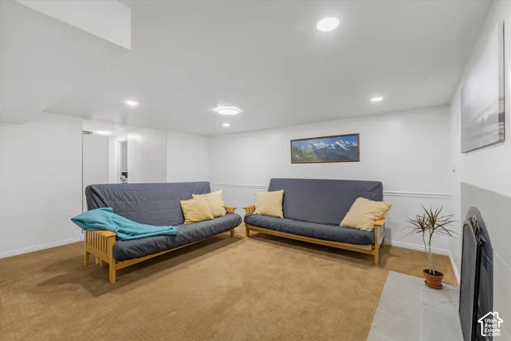 Recessed lighting, white walls, carpeted flooring, and a tiled fireplace surround