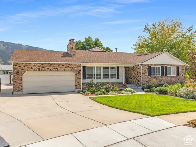 Brick exterior with a two-car garage, concrete driveway, and a well-maintained lawn