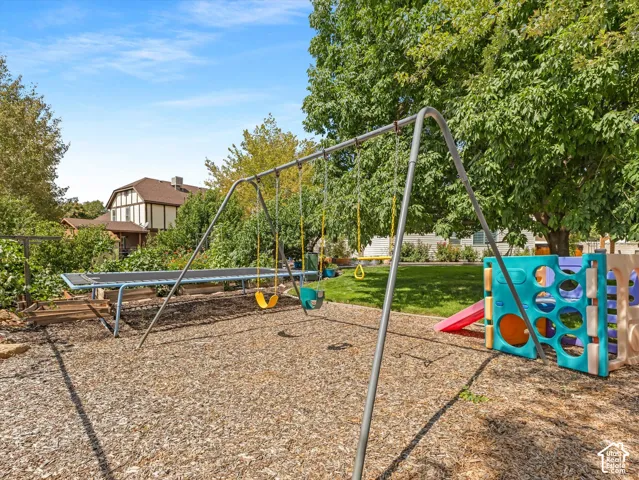 Expansive backyard featuring a swing set, multi-activity play structure, and in-ground trampoline