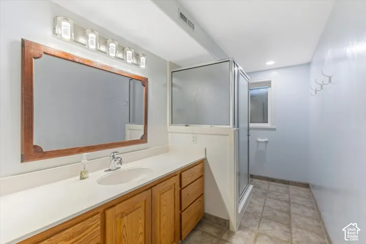 Single vanity with wood-finish cabinetry, integrated sink, and white countertop