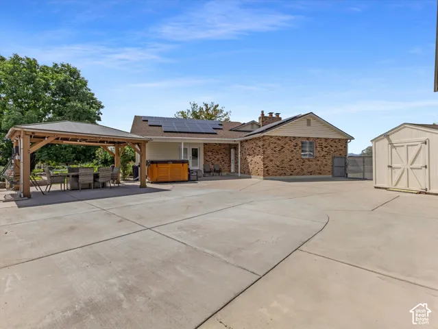 Expansive concrete patio with a covered gazebo, hot tub, and detached storage shed