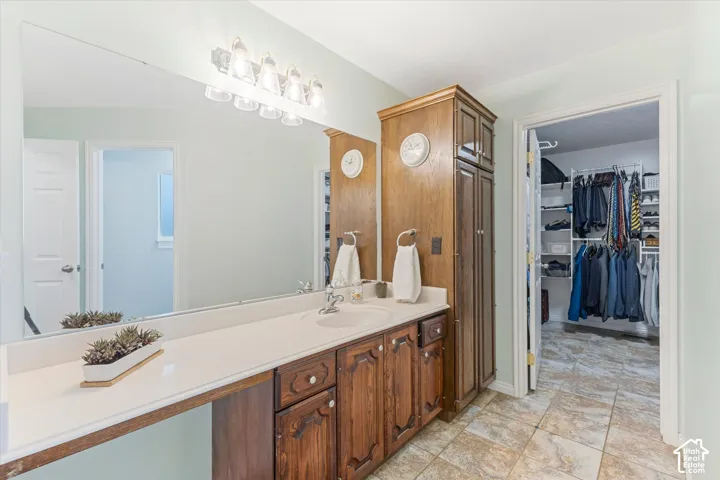 Bathroom vanity with wood-finish cabinetry, integrated single sink, and white countertop