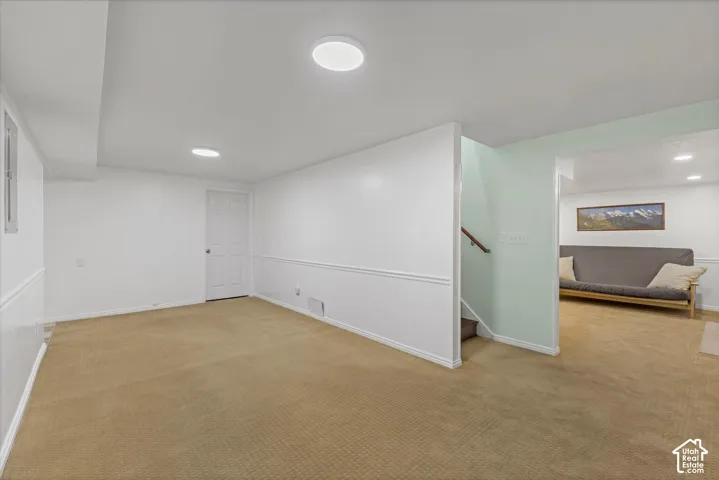 Recessed lighting fixtures illuminate the space, complemented by a white paneled door and light-toned carpeting