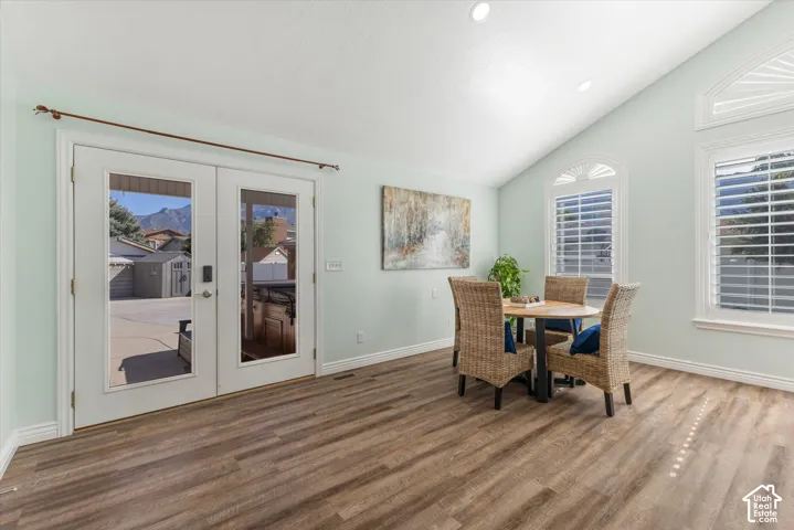 Wood-finish flooring, vaulted ceiling, recessed lighting, and white frame french doors