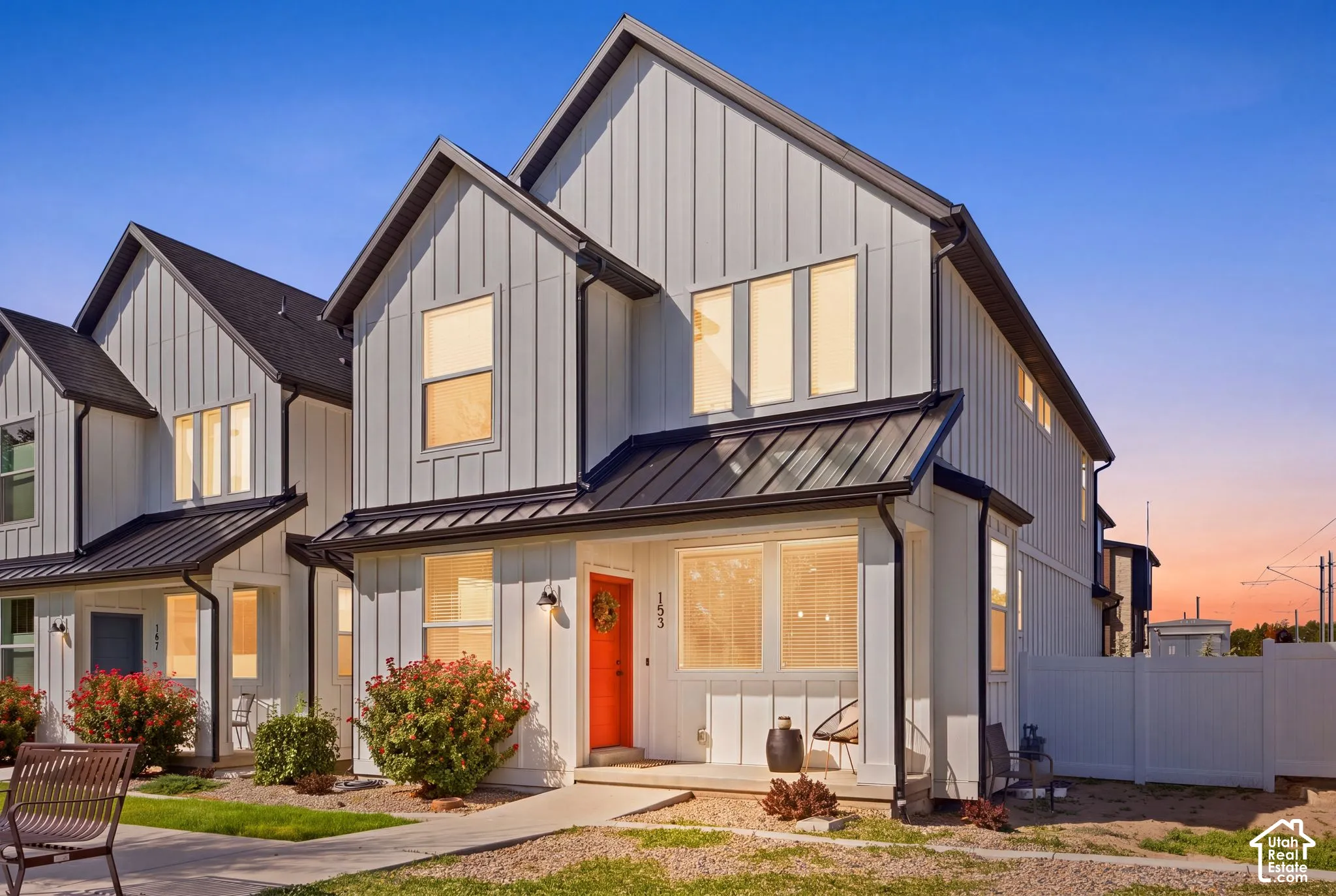 Modern farmhouse exterior featuring vertical board and batten siding, multiple gables, a black metal roof, and an orange front door