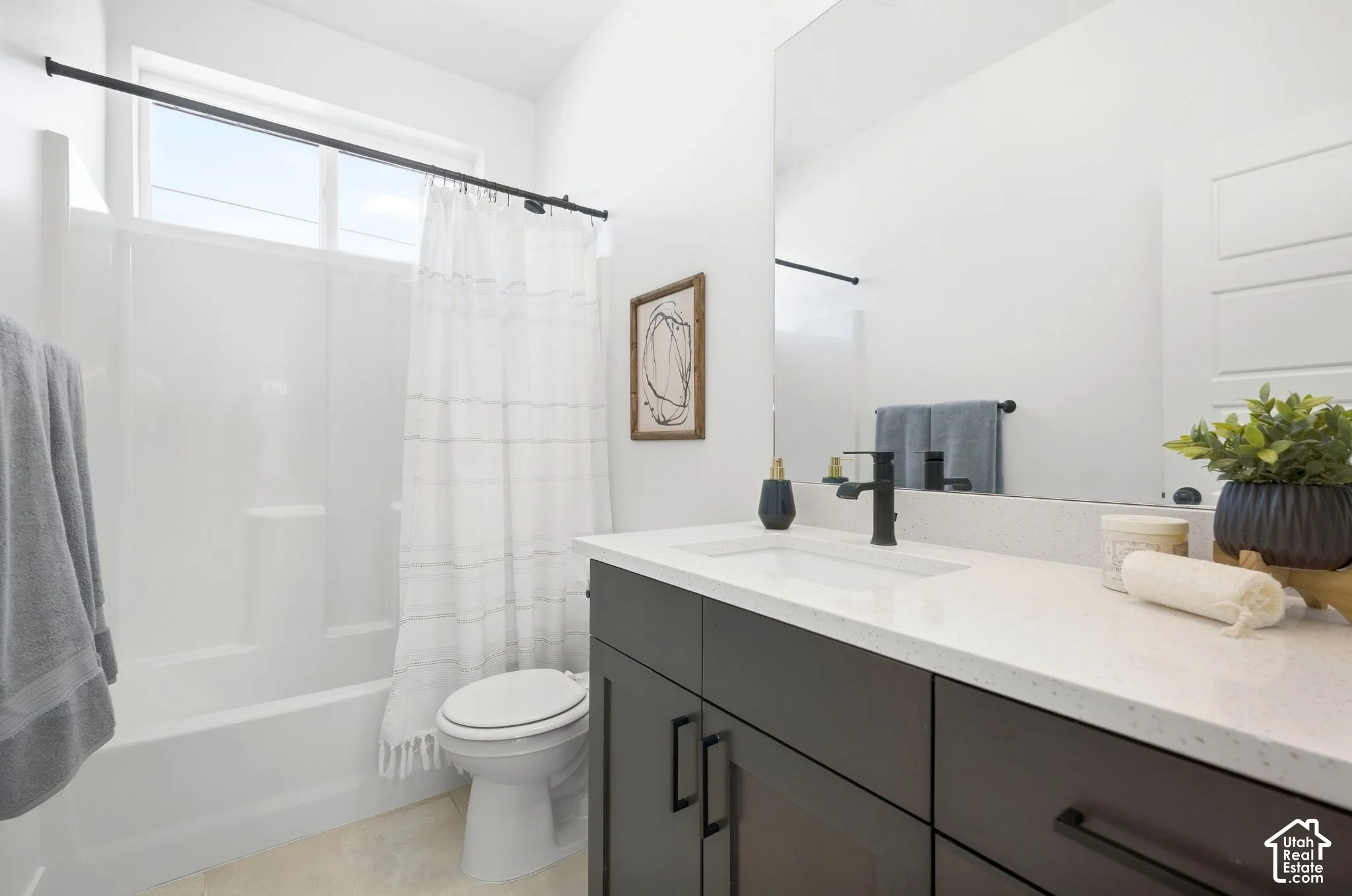 Bathroom featuring a white bathtub, a single vanity with dark cabinetry, a white countertop, and a large mirror