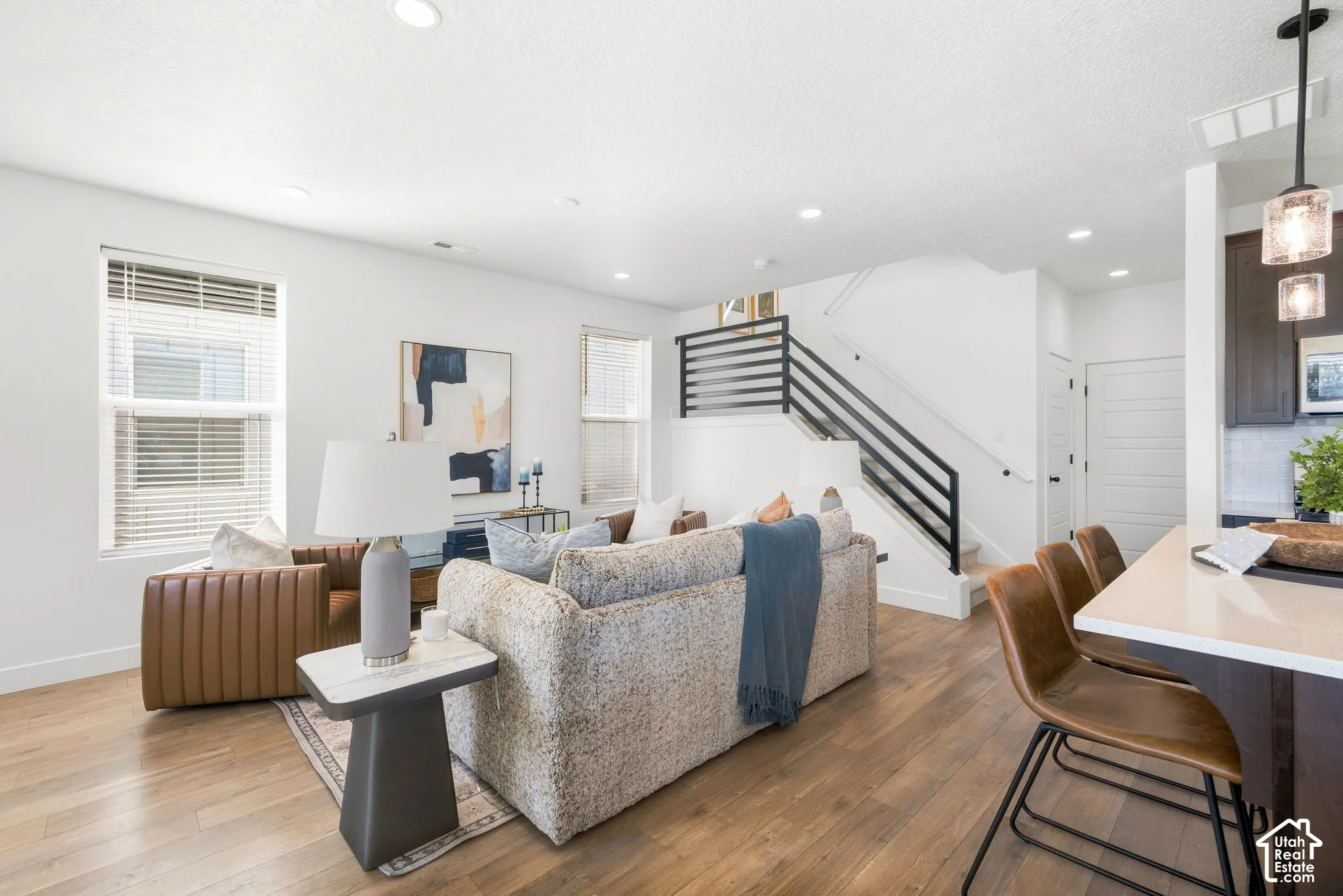 Open-concept living space with wood-finish flooring, recessed lighting, and white walls