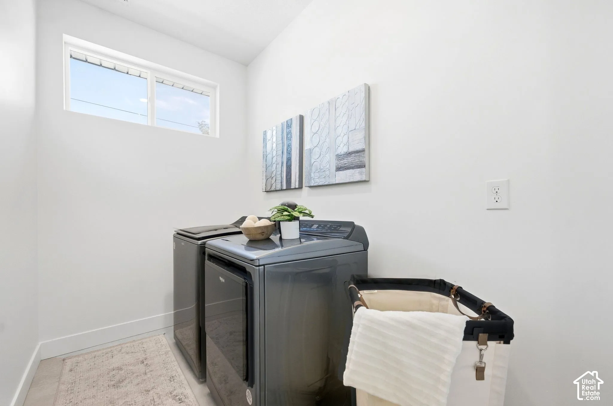 Laundry area with a high window, white walls, and light-colored flooring
