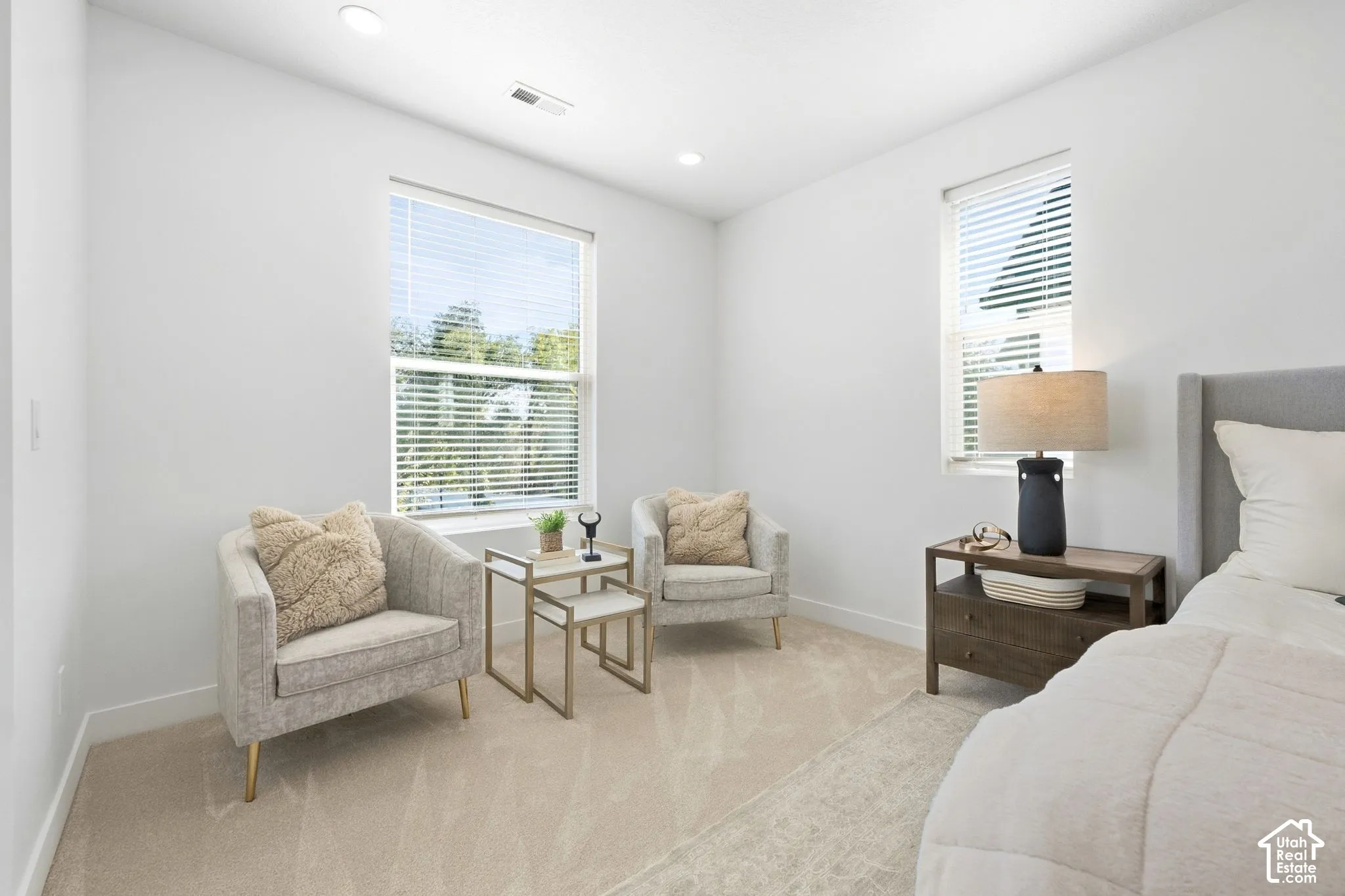 Primary bedroomRecessed ceiling lighting, light neutral-toned carpeting, window blinds, and multiple windows