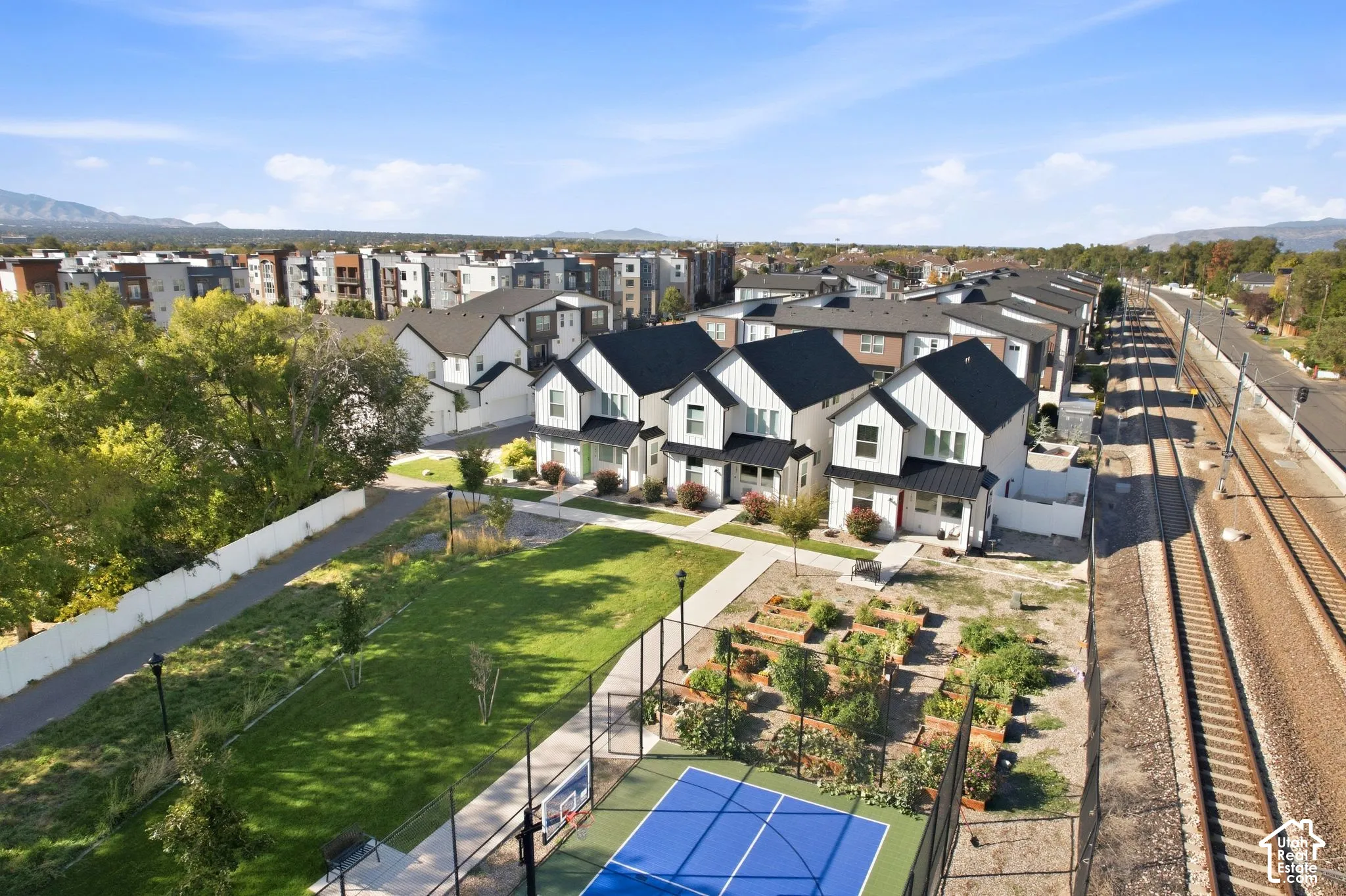 Modern townhome community featuring a recreational court, expansive green space, garden plots, and contemporary architectural design
