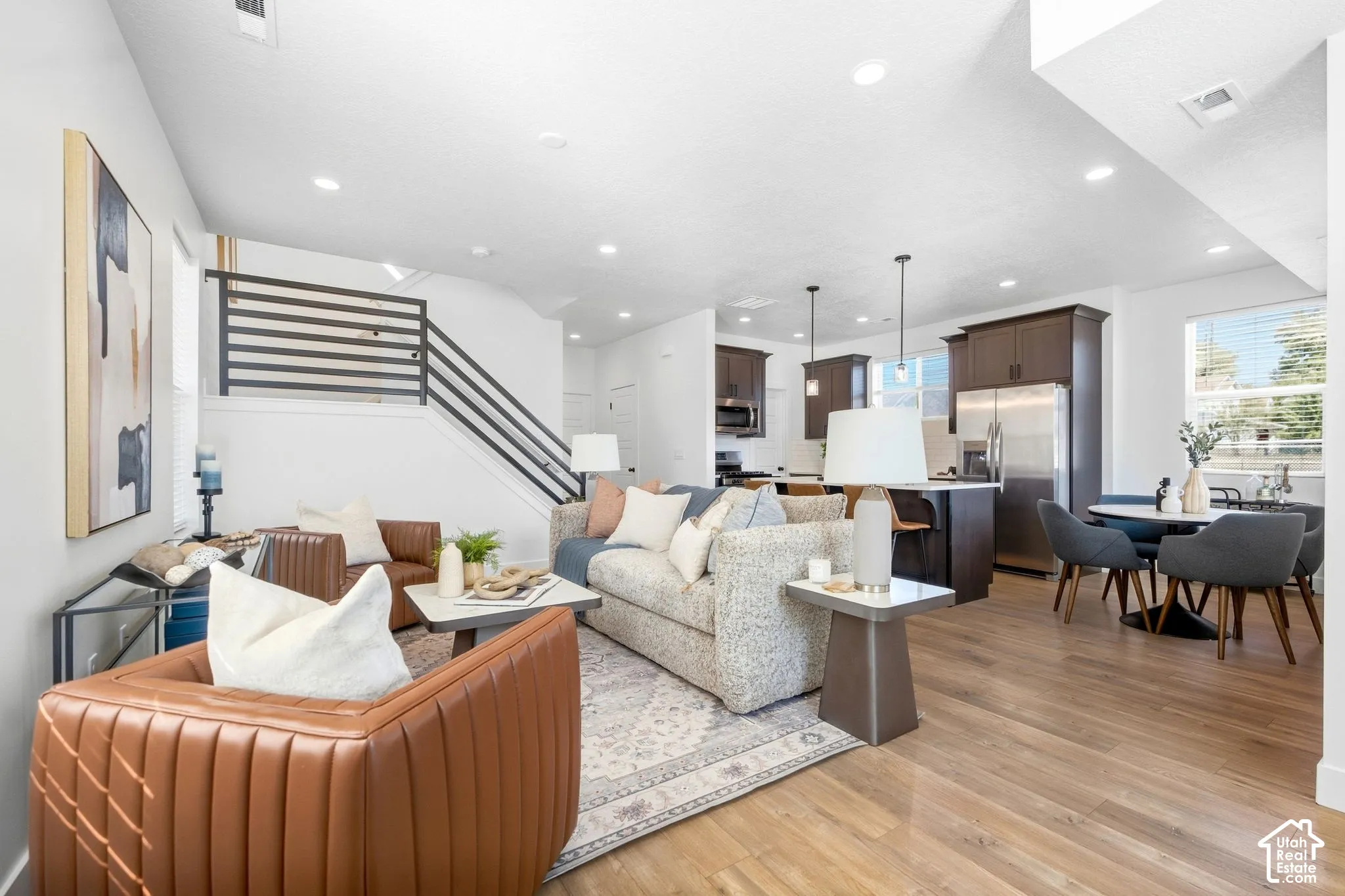 Open-concept living space with wood-finish flooring, recessed lighting, and a modern horizontal stair railing
