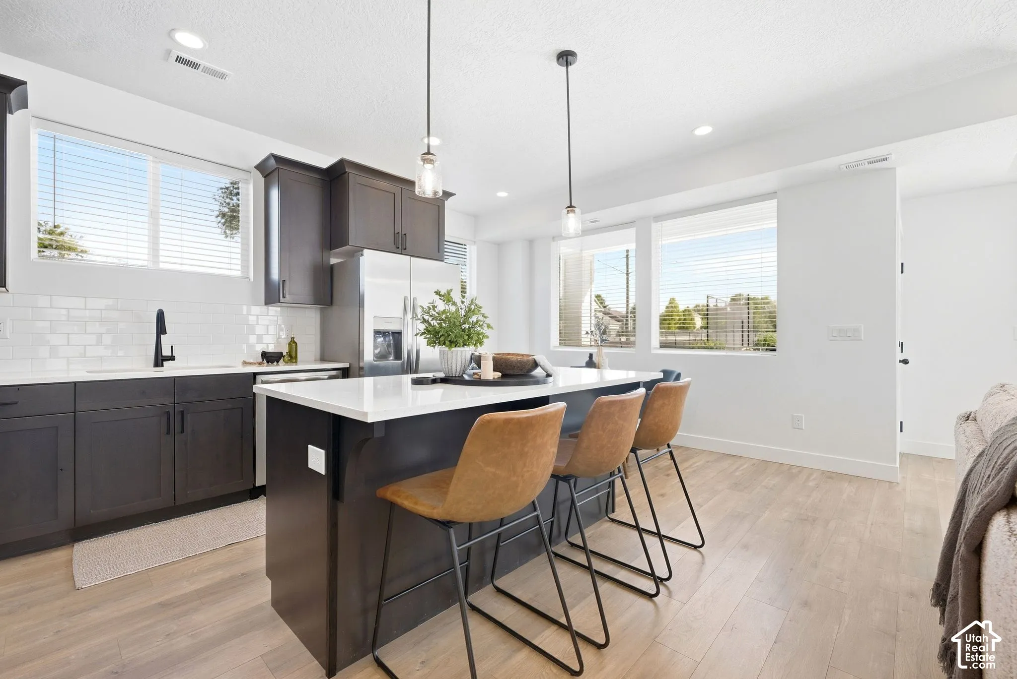 Kitchen featuring dark wood-finish cabinetry, white subway tile backsplash, white countertops, and wood-finish flooring