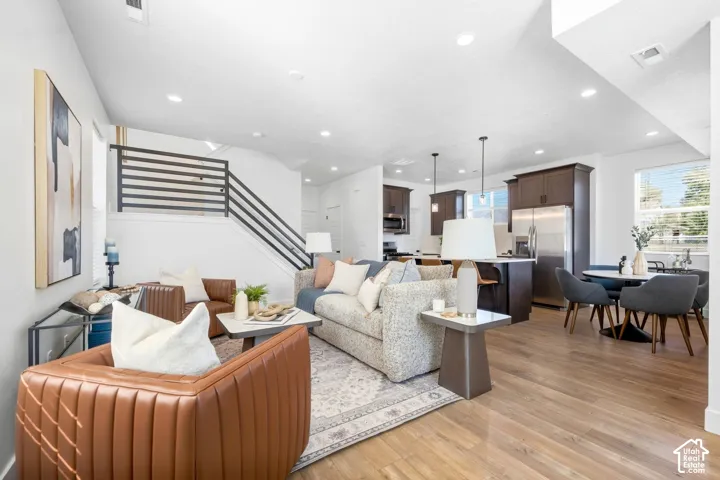 Open-concept living space with wood-finish flooring, recessed lighting, and a modern horizontal stair railing