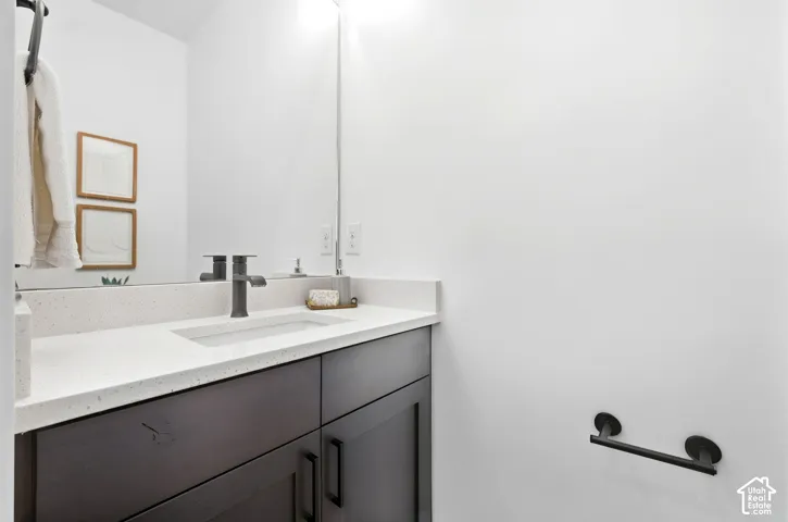 Dark wood-finish vanity with a light-toned countertop, integrated rectangular sink, and matte black faucet