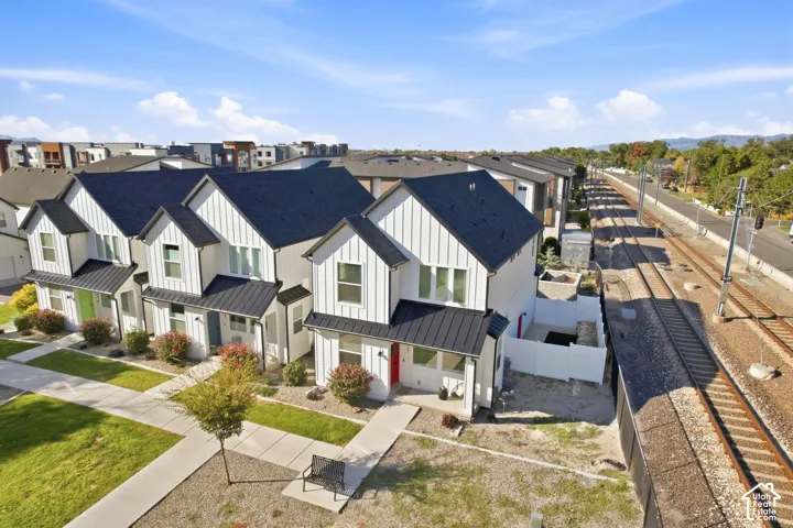 Modern farmhouse-style townhome featuring white vertical siding, black-pitched roofs, and a red front door