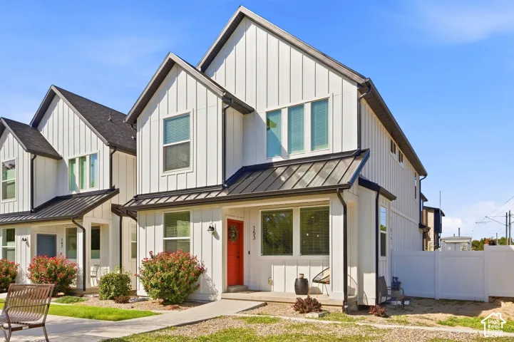 Modern farmhouse exterior with vertical white siding, black-frame windows, and a prominent red entry door