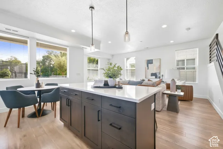Open-concept living space with wood-finish flooring, recessed lighting, and multiple windows