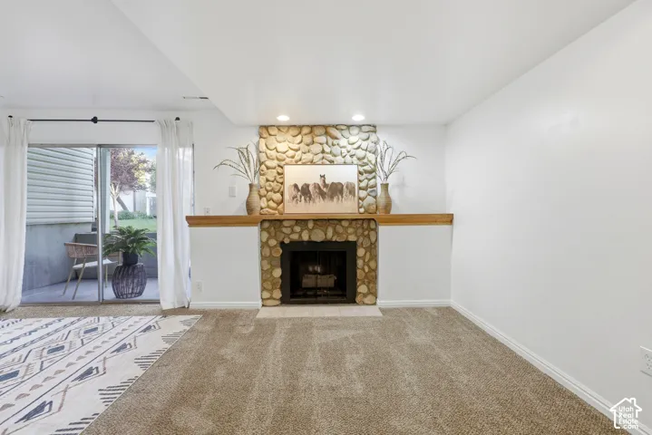 Stone-clad fireplace with a wood mantle, sliding glass door, and recessed lighting