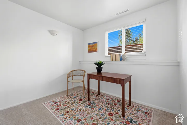 Carpeted room featuring white walls, a single window with horizontal blinds, and a built-in wall light fixture