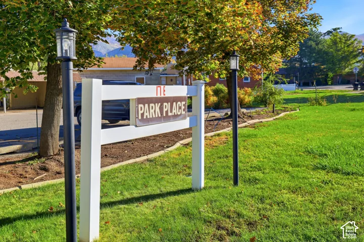 White architectural sign featuring "PARK PLACE" lettering and two black lantern-style post lights