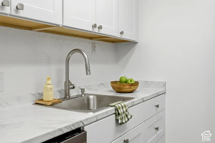 White cabinetry with square pull hardware, a stainless steel sink, a pull-down faucet, and a patterned tile backsplash