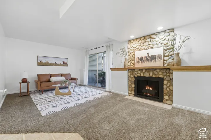 Stone-clad fireplace with a wood mantle, recessed lighting, and sliding glass door