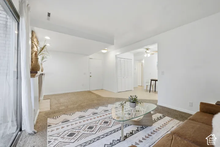Living area with carpeting, recessed lighting, and a stone-faced fireplace with a mantel