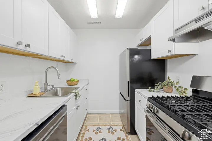 White shaker cabinetry, stainless steel sink, sleek stainless steel appliances, and light-toned countertop surfaces