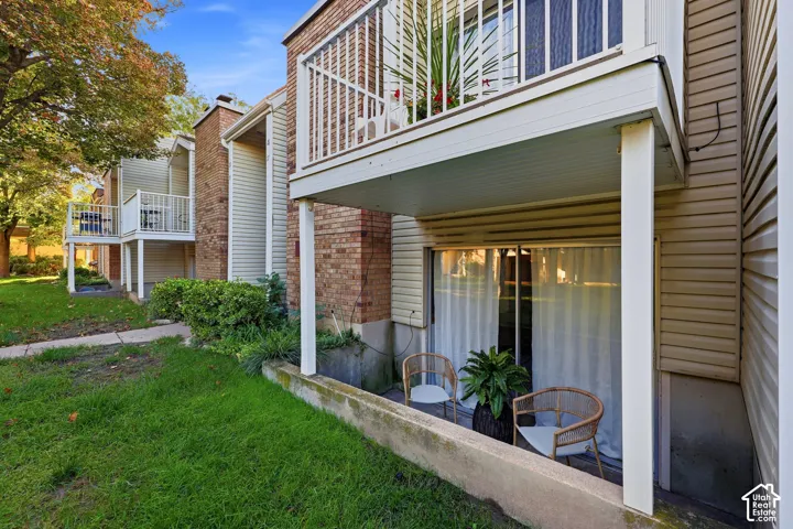 Brick and siding exterior with multiple balconies, a lower patio, and a grass area