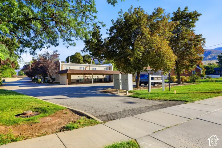 Paved parking area, covered parking structure, established trees, mailboxes, and manicured landscaping