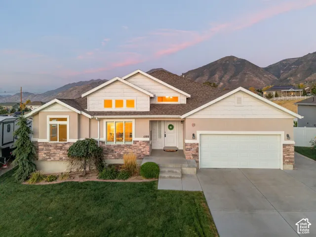 Single-story residence featuring a two-car garage, stone facade accents, and an expansive concrete driveway