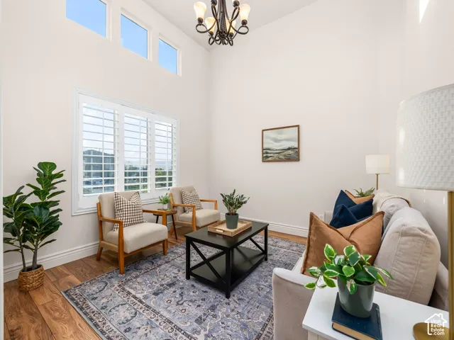 Vaulted ceiling with a wrought iron chandelier, wood-finish flooring, and crisp white walls
